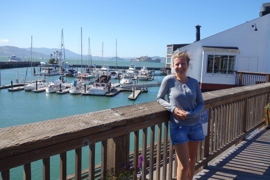 Kiki steht am Pier in San Francisco. Im Hintergrund Alcatraz